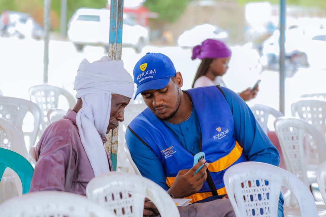 Service client de proximité : un agent Konoom aide un utilisateur âgé au Cameroun.