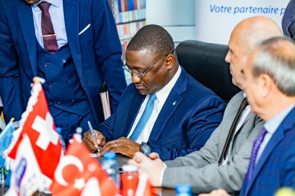 Un responsable ou signataire (vêtu d'un costume bleu et d'une cravate bleue) appose sa signature sur les documents officiels marquant le partenariat exclusif entre le Port Autonome de Kribi et BGFIBank Cameroun.