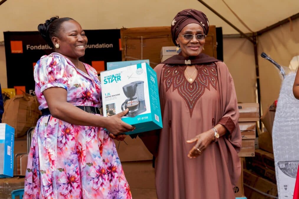 La ministre de la Promotion de la Femme et de la Famille remettant tout sourire un carton de machine à café à une responsable de centre de formation.