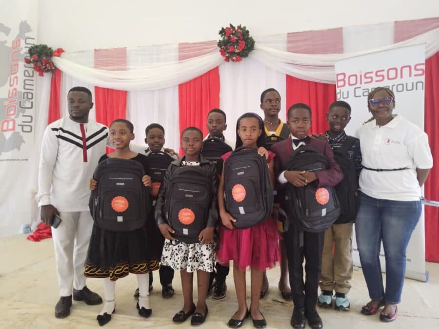 Groupe restreint de jeunes élèves diplômés en tenue de fête tenant leurs cartables étanches offerts dans le cadre du programme RSE.