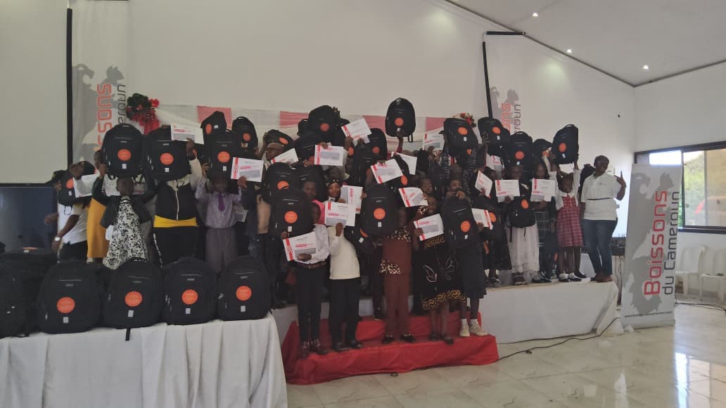 Rassemblement festif des élèves du Nord-Ouest sur scène brandissant leurs sacs à dos techniques et certificats de mérite à Bamenda.
